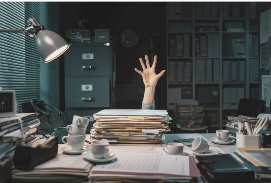 A person is reaching for the top of a stack of papers.