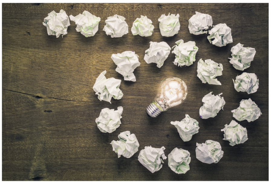 A group of crumpled papers with an illuminated light bulb in the middle.