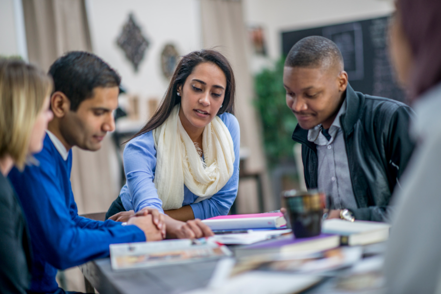 Three people sitting at a table looking at papers.