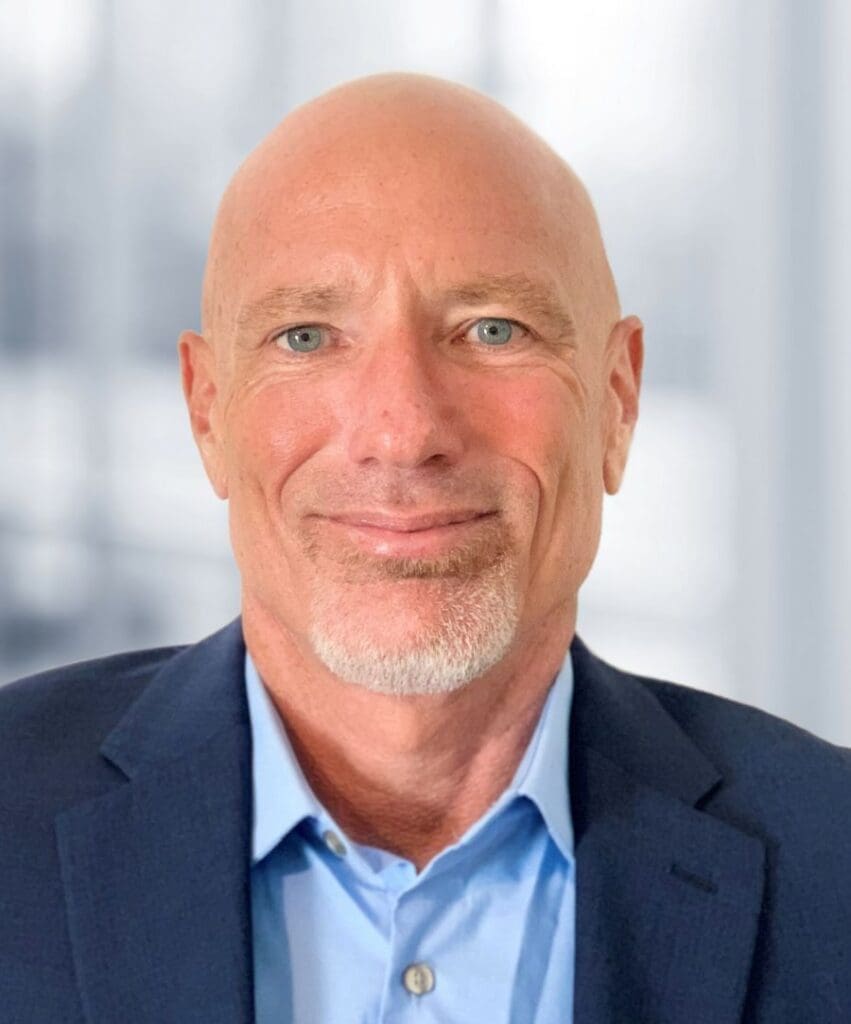 A man with a shaved head and beard wearing a suit.